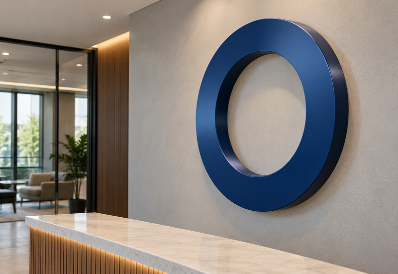 Blue dimensional metal ring logo with curved sidewalls mounted on a reception wall