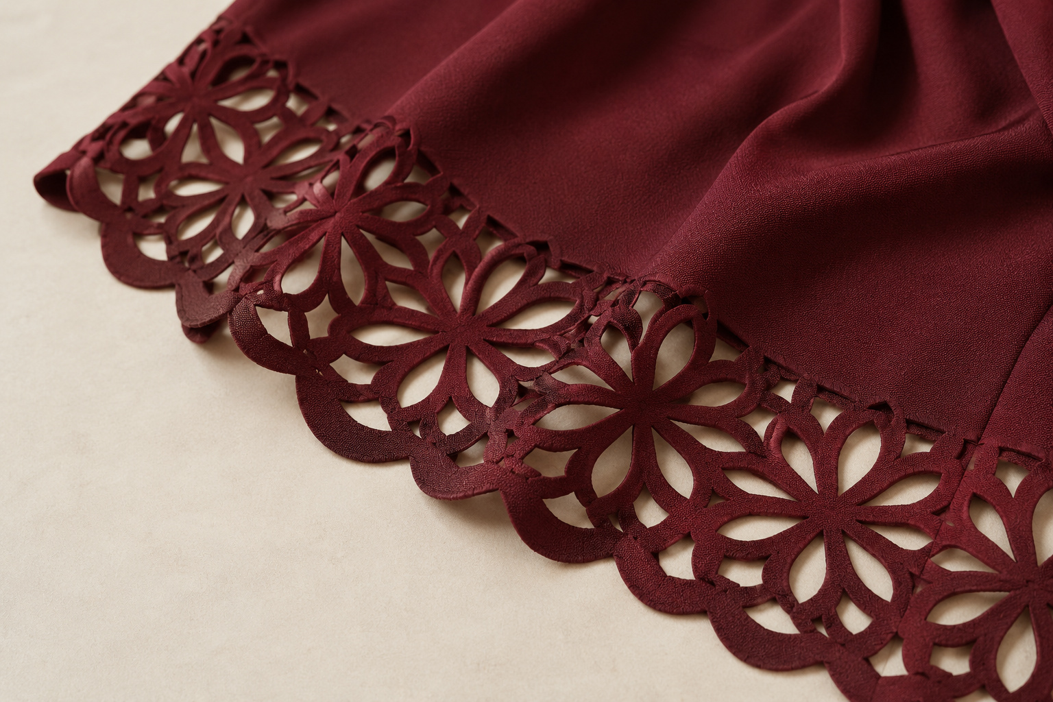 Burgundy fabric panel with floral laser-cut openings and a decorative scalloped edge.