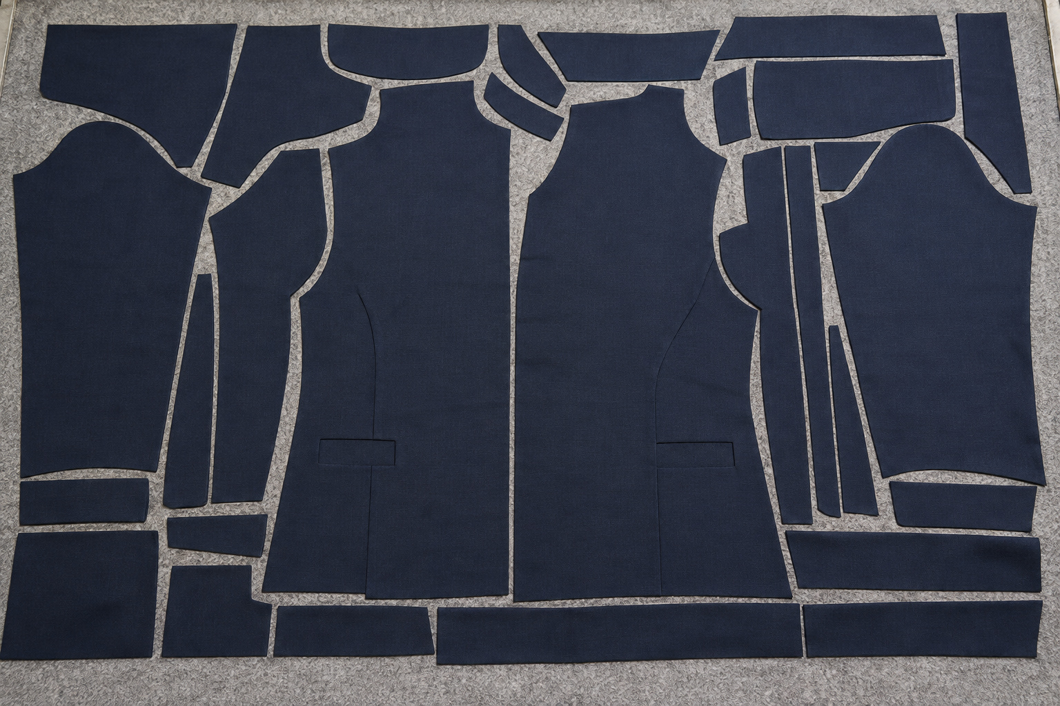 Garment pattern shapes nested within a navy fabric sheet on a cutting bed